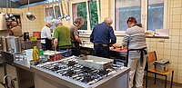 Das Bild zeigt Mitarbeitende der Suppenküche bei der Vorbereitung eíner Mahlzeit